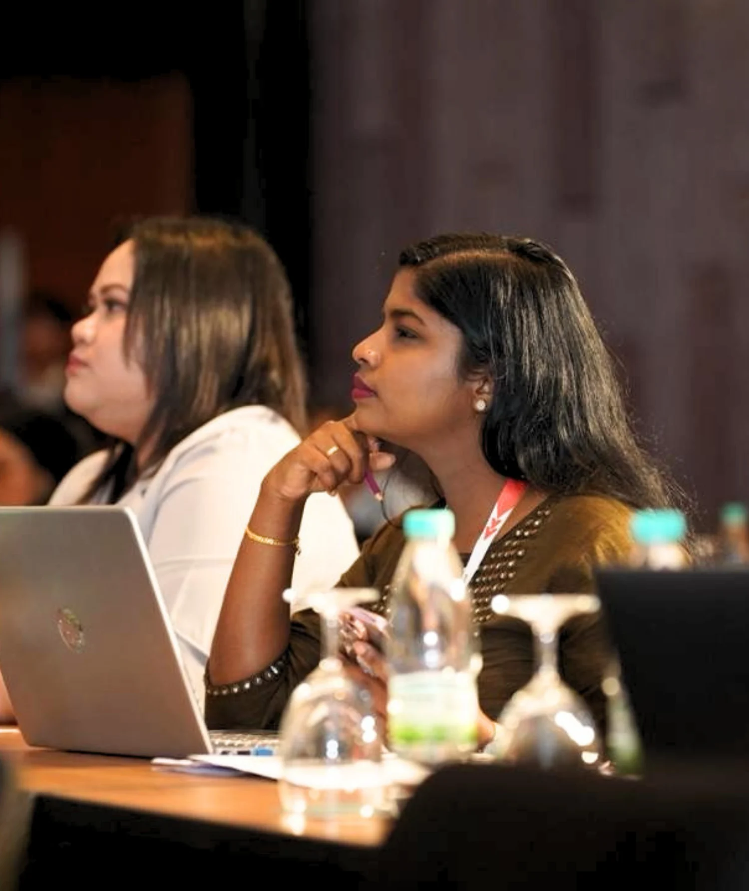 Pauline Suzanna attending a professional meeting and taking notes while seated with a laptop.